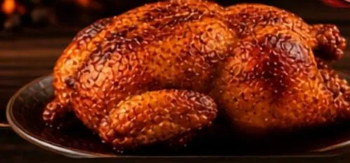 Pollo entero a la brasa dorado sobre bandeja negra